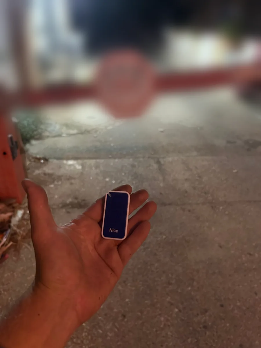 שכפול שלט Nice לשער חשמלי של חניה — השלט ביד מול מחסום החניה, סילבר מנעולנות
